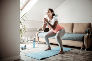 Smiling curvy lady doing wide squats while getting in order