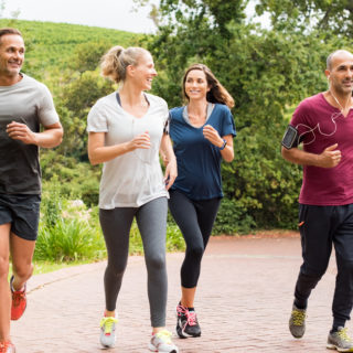 Healthy group of people jogging on track in park. Happy couple enjoying friend time at jogging park while running. Mature friends running