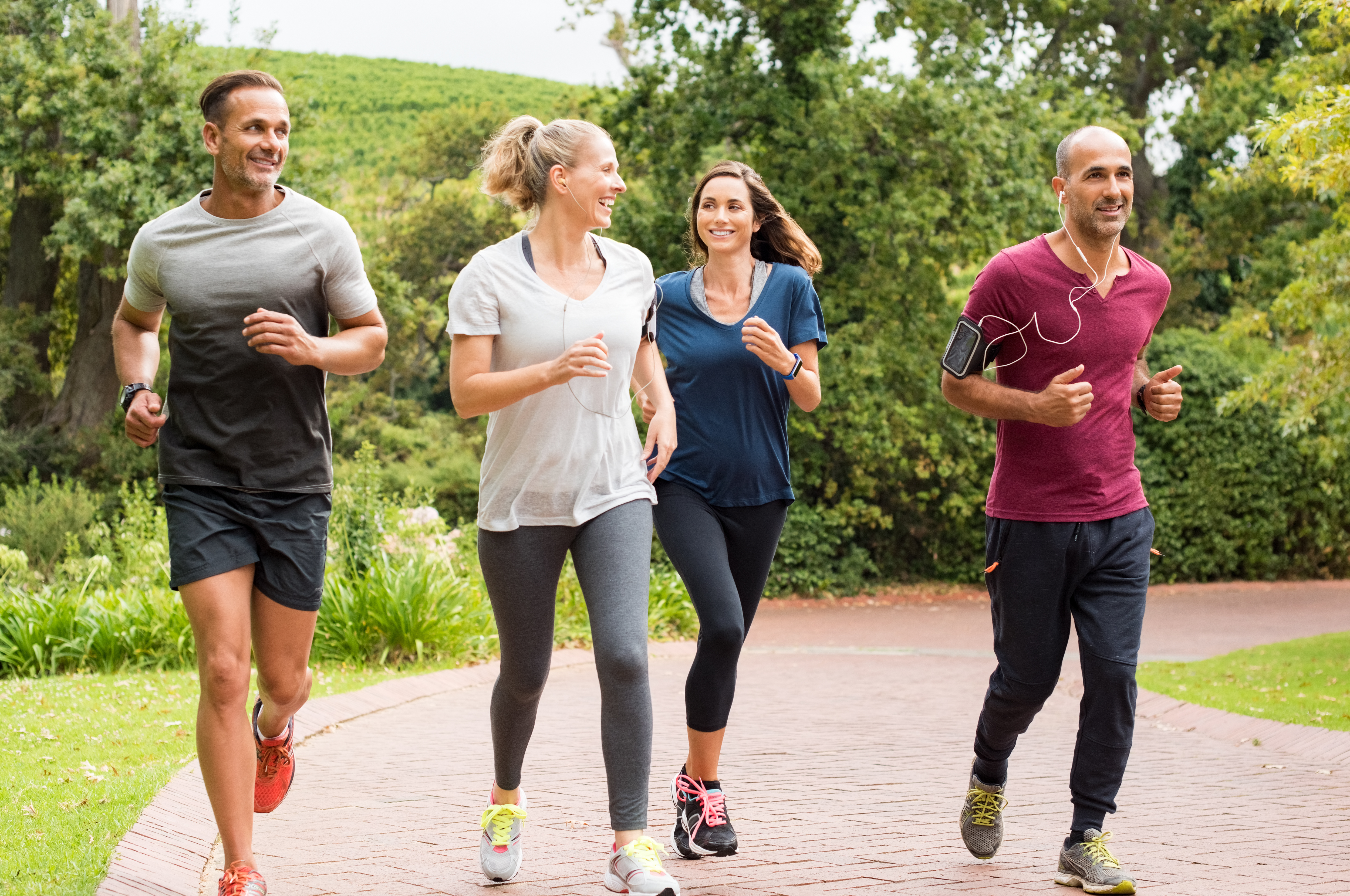Healthy group of people jogging on track in park. Happy couple enjoying friend time at jogging park while running. Mature friends running