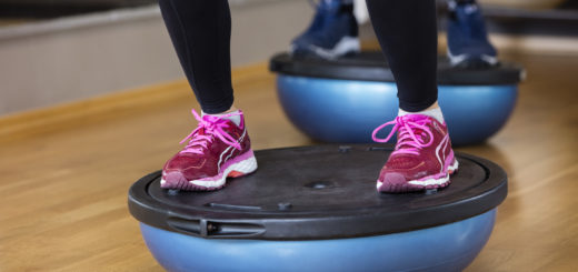 Low section of woman standing on bosu ball in health club