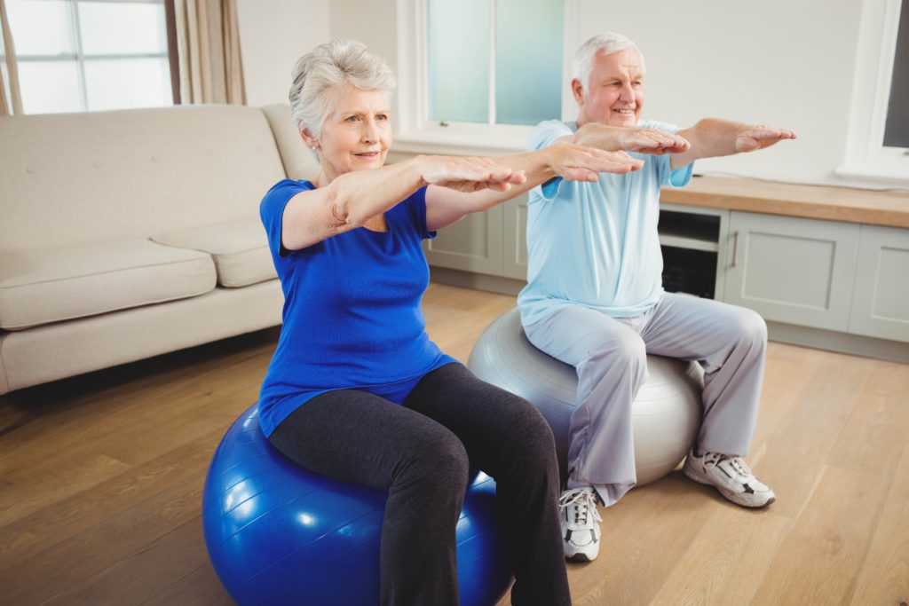 elderly couple sitting on ball