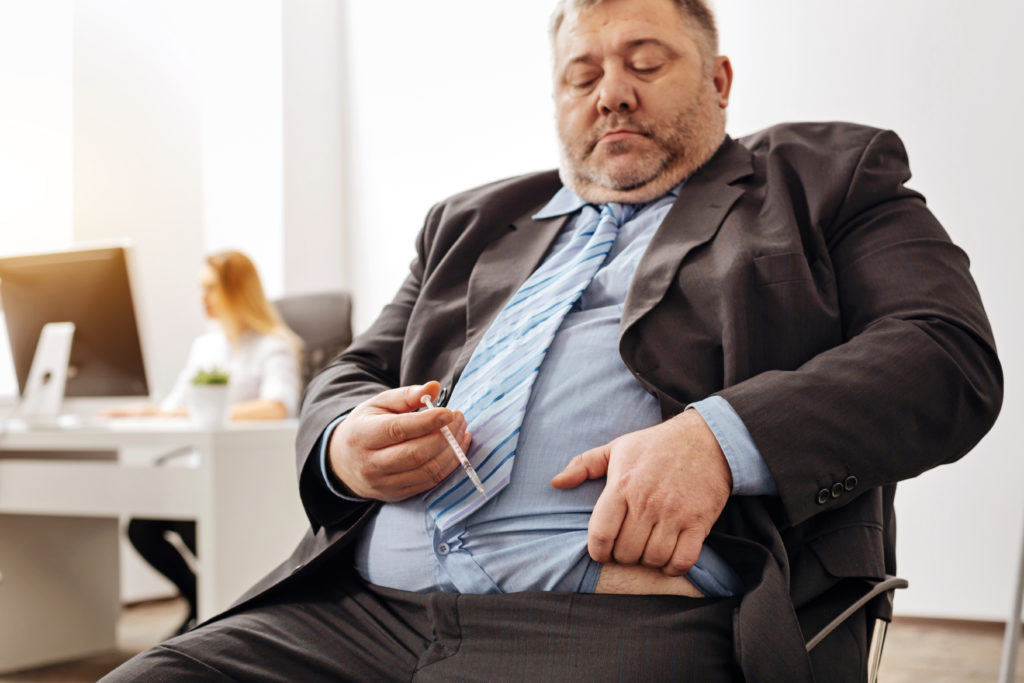 Overweight guy injecting insulin