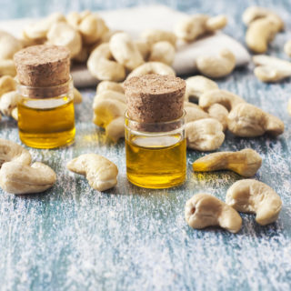 cashew nuts and oil in bottle on wooden background. Selective focus